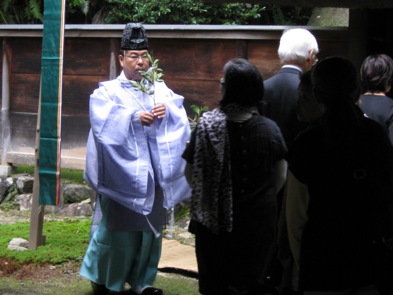 A priest prepares to hand a tamagushi offering to participants at a ritual.