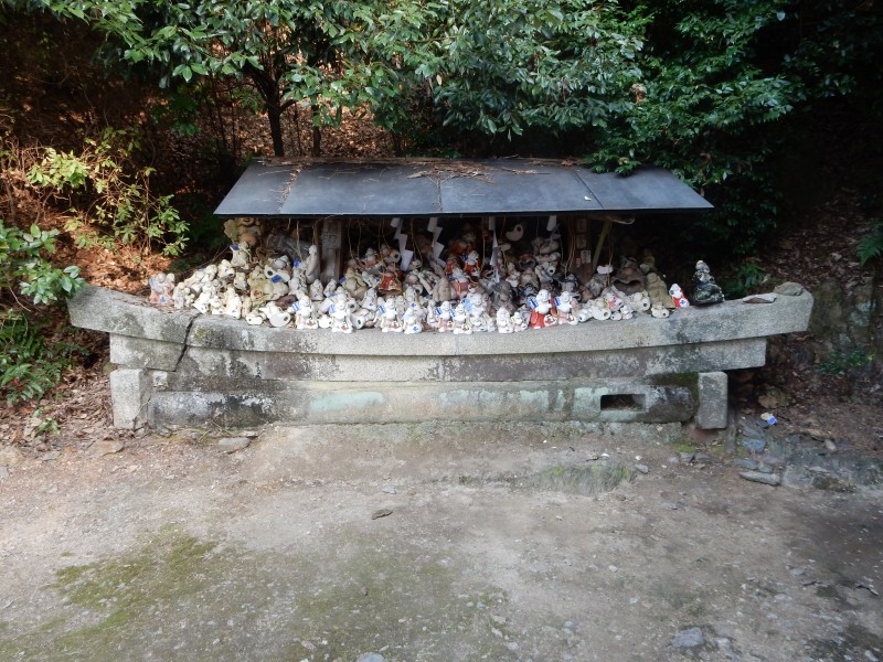 Disposal of old Hotei figurines, in a vessel shaped like a boat. The Seven Lucky Deities are often pictured in a Treasure Boat... here the boat is transporting the figurines to another world. 