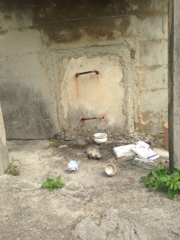 A typical family tomb, with opening for bones to be placed inside and the remains of offerings and sake drinking