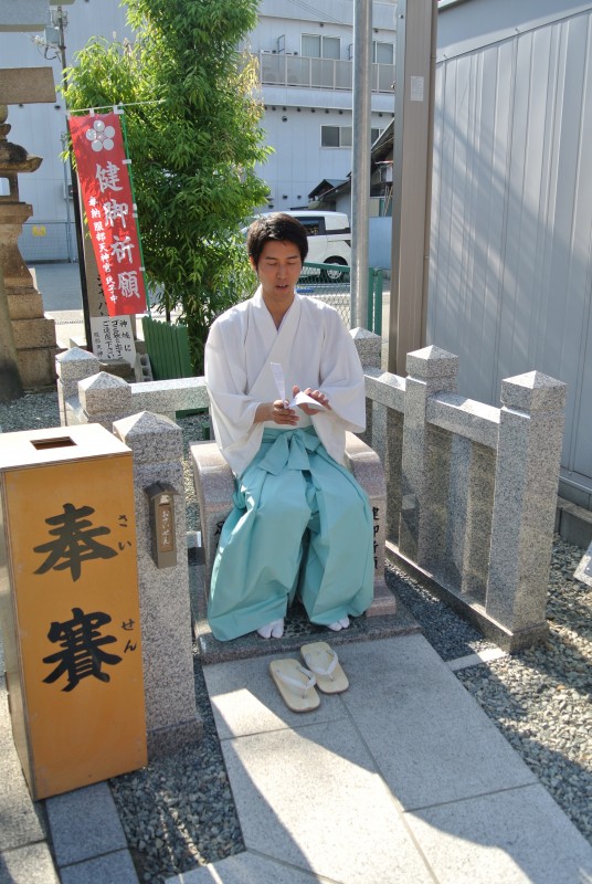 Taishi Kato demonstrates the leg protecting stone chair in his father's shrine of Hattori Tenjingu, 
